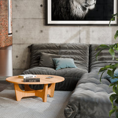 Solid oak coffee table used as a low table in a living room seating area, paired with a lounge chair and soft textiles