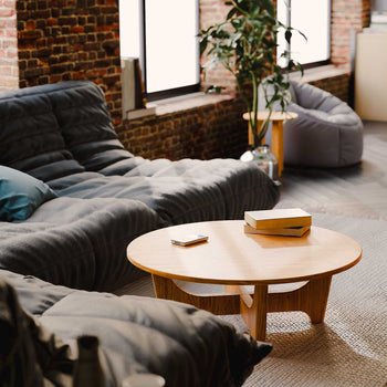 Modern living room with a wooden coffee table, gray sectional sofa and brick wall.