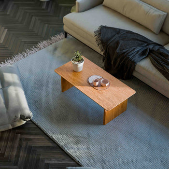 Solid oak coffee table used as a low table in a living room seating area, paired with a lounge chair and soft textiles