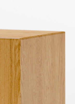 Modern solid wood end table in oak with clean lines and natural finish, styled beside a sofa in a minimalist living room