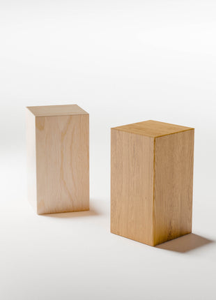 Modern wood furniture piece featuring a solid wood side table in oak, placed beside a bed as a compact nightstand alternative