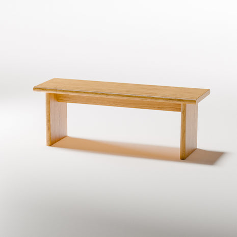 Solid oak nightstand with rounded corners and open storage shelf, shown from angled side view in a cozy contemporary bedroom