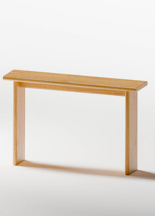 Modern solid wood console table in oak with smooth edges, styled beneath a round mirror in a Scandinavian entryway