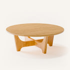 Modern solid wood coffee table in oak with clean lines and natural grain, centered in a minimalist living room with a neutral sofa and soft area rug