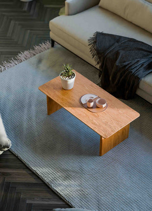 Solid oak coffee table used as a low table in a living room seating area, paired with a lounge chair and soft textiles
