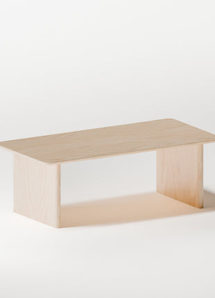 Minimalist solid wood coffee table in maple with simple rectangular shape, styled in a bright living room with modern wood furniture