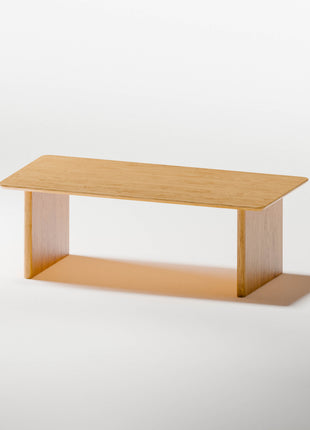 Modern wood coffee table in solid oak placed in front of a light fabric sofa, styled with a tray and candle in a cozy living room