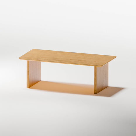 Modern wood coffee table in solid oak placed in front of a light fabric sofa, styled with a tray and candle in a cozy living room