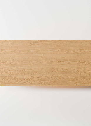 Solid oak coffee table used as a low table in a living room seating area, paired with a lounge chair and soft textiles