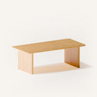 Solid oak coffee table used as a low table in a bedroom seating area, paired with a lounge chair and soft textiles