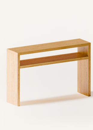 Modern solid wood console table in oak with clean lines and natural finish, styled in a minimalist entryway with mirror and ceramic decor