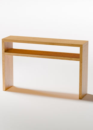 Modern solid wood console table in oak with clean lines and natural finish, styled in a minimalist entryway with mirror and ceramic decor