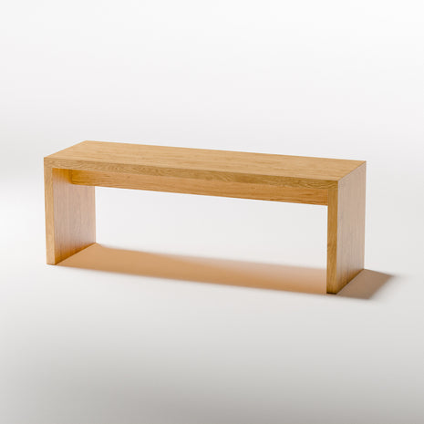 Modern wood nightstand in solid oak featuring natural finish and simple design, placed beside a bed in a warm Scandinavian style bedroom