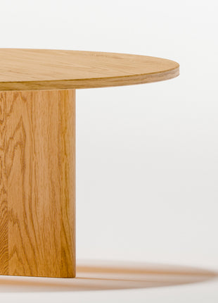 Solid oak coffee table used as a low table in a living room seating area, paired with a lounge chair and soft textiles
