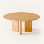 Modern wood coffee table in solid oak placed in front of a light fabric sofa, styled with a tray and candle in a cozy living room