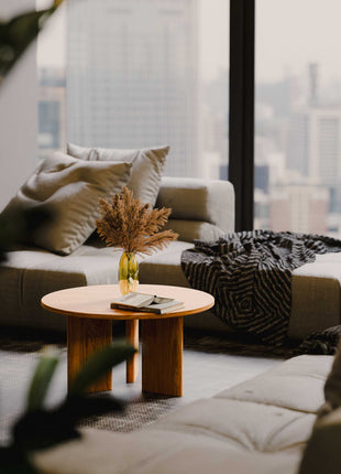 Modern living room with a sofa, coffee table, and cityscape view.