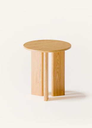 Modern solid wood end table in oak with clean lines and natural finish, styled beside a sofa in a minimalist living room