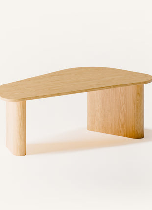 Modern solid wood coffee table in oak with clean lines and natural grain, centered in a minimalist living room with a neutral sofa and soft area rug