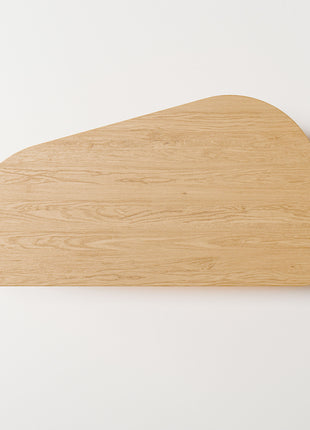Modern solid wood coffee table in oak with clean lines and natural grain, centered in a minimalist living room with a neutral sofa and soft area rug